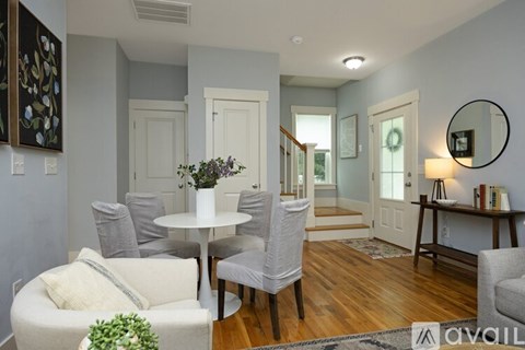 A living room with a white couch and a round table with a vase of flowers on it.