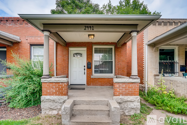A house with a white door and a porch with a stone pillar.