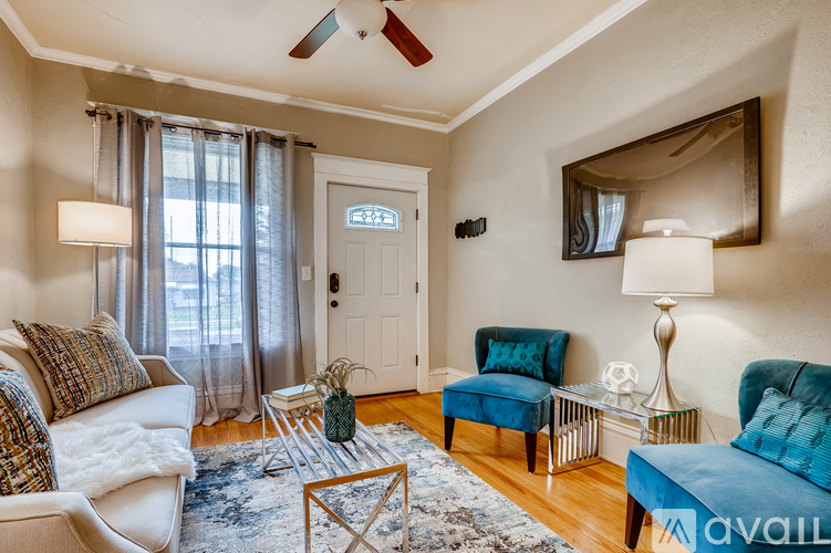 A living room with a white couch, a blue chair, and a rug.