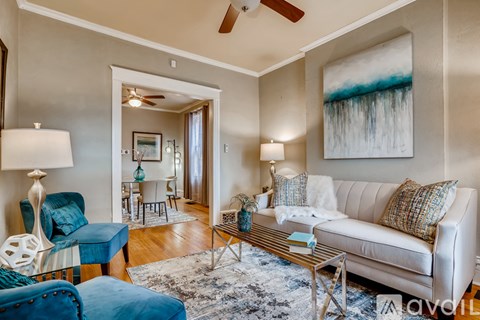A living room with a white couch and a blue chair.