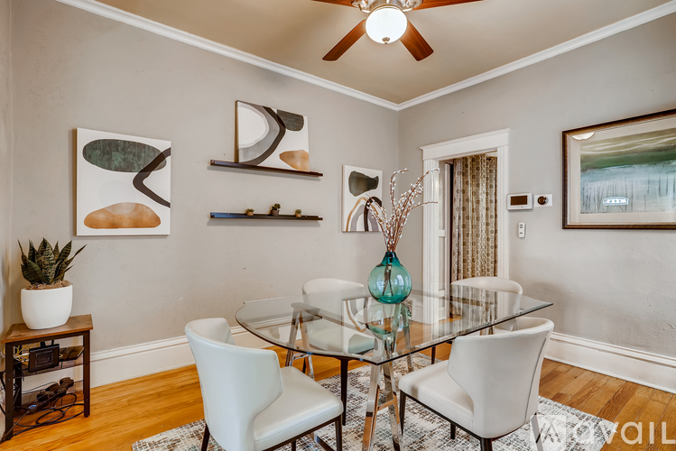 A modern dining room with a glass table and white chairs.