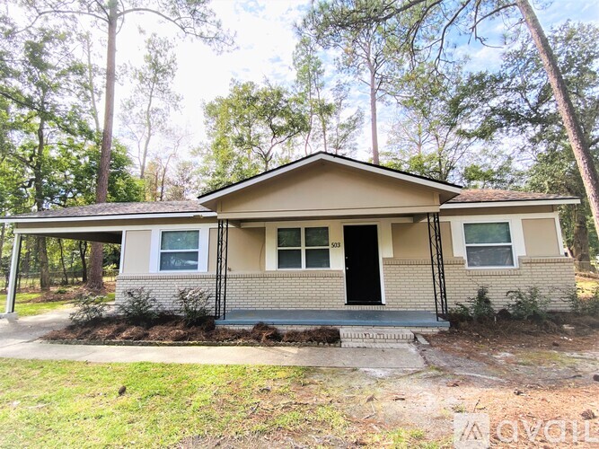 A house with a black door and windows is surrounded by trees.