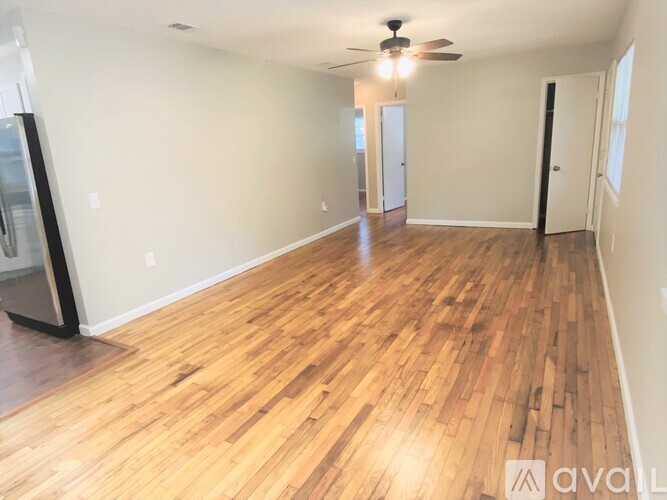 A spacious room with wooden flooring and a ceiling fan.