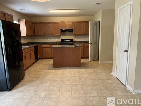 A kitchen with wooden cabinets and a black refrigerator.