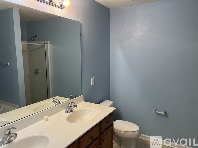 A bathroom with blue walls has a toilet and a sink with a mirror above it.