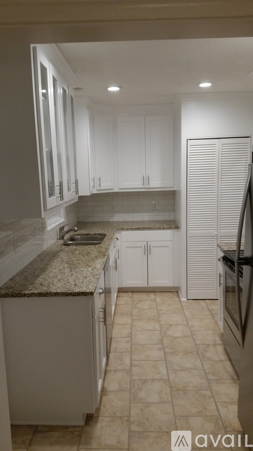 A kitchen with white cabinets and a granite countertop.