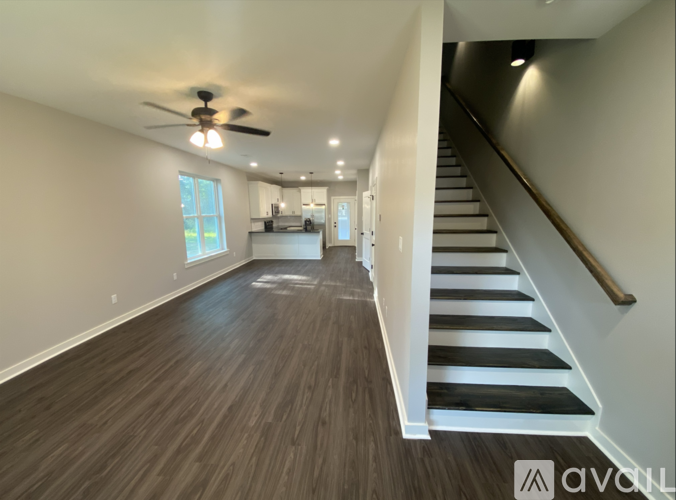 A spacious room with wooden flooring and a staircase leading to another level.