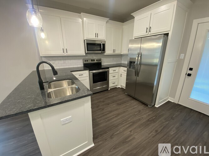 A kitchen with white cabinets and a stainless steel refrigerator.
