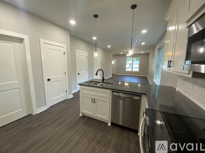 A modern kitchen with a stainless steel dishwasher and black countertops.