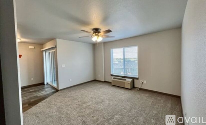 A spacious room with a ceiling fan and a window with blinds.