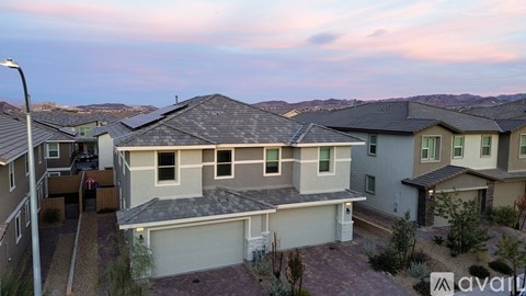 A house with a garage is in the foreground of a residential area.