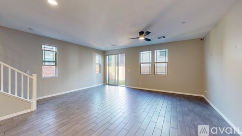 A spacious room with wooden flooring and a ceiling fan.