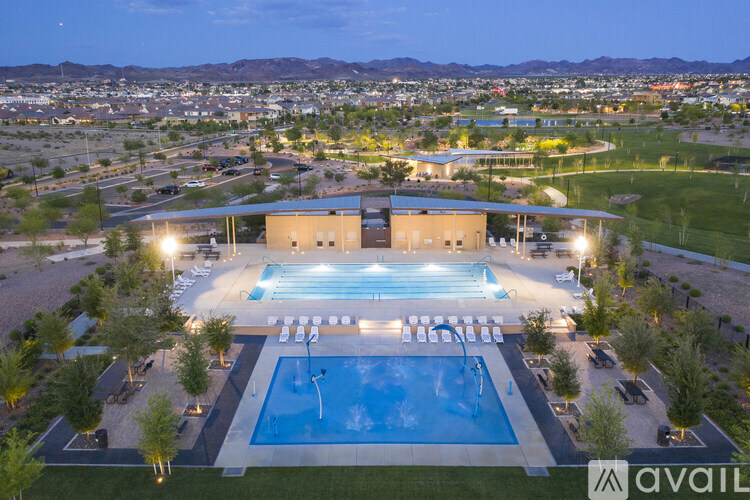 An aerial view of a swimming pool surrounded by a grassy area and buildings in the distance.