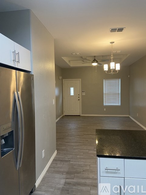 A kitchen with a stainless steel refrigerator and a black countertop.