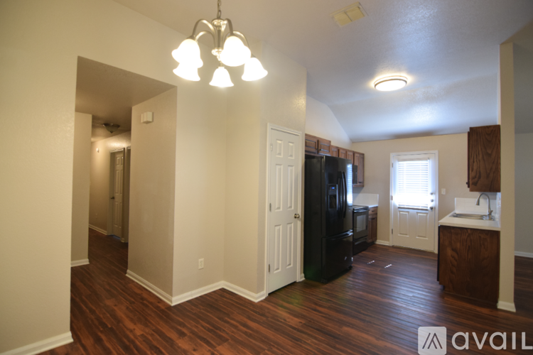 A kitchen with a black fridge and wooden floors.