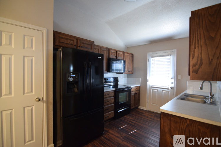 A kitchen with a black fridge and wooden cabinets.