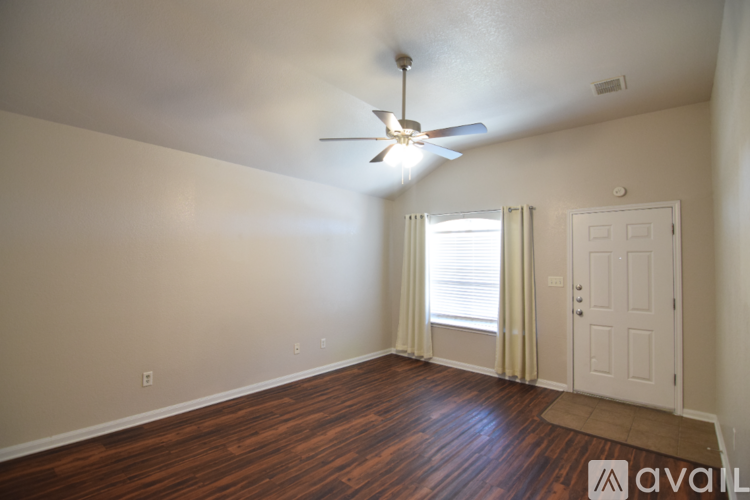A room with a ceiling fan and wooden flooring.