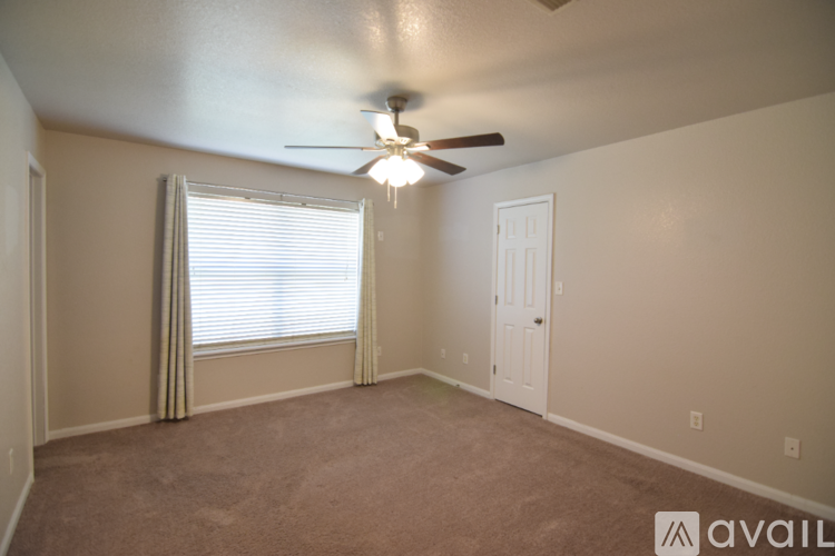 A room with a ceiling fan and a window with curtains.