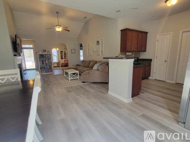 A spacious living room with a kitchen area in the background.