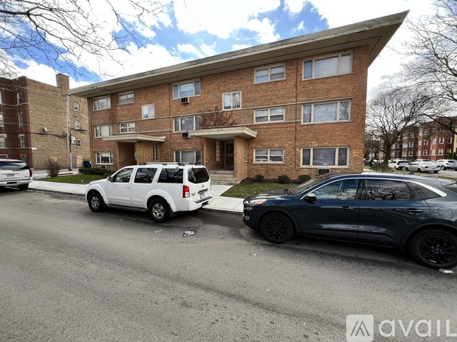 A white SUV is parked in front of a brick apartment building.