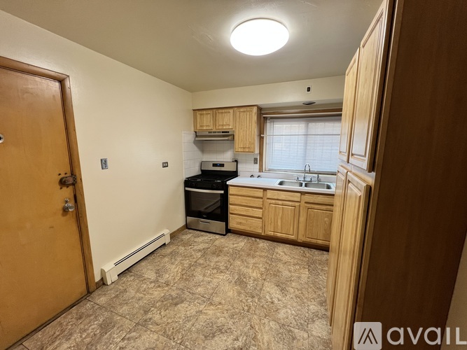 A kitchen area with a sink, stove, and cabinets.