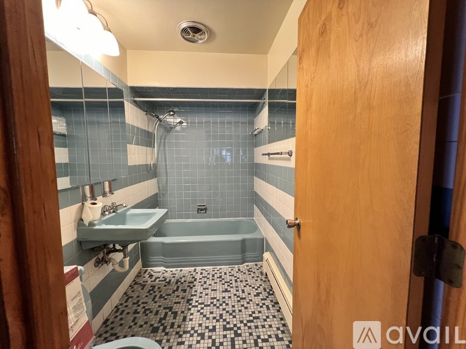 A bathroom with a blue tiled shower and a wooden door.