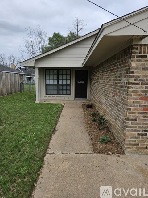 A house with a brick wall and a black door.