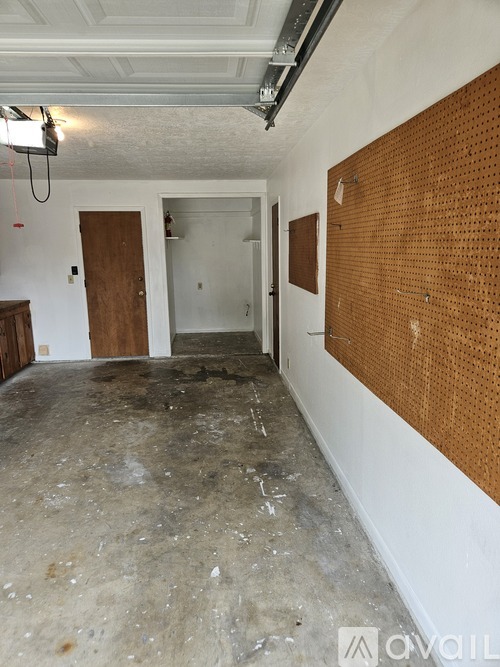 A room with a brown pegboard on the wall and a doorway leading to another room.