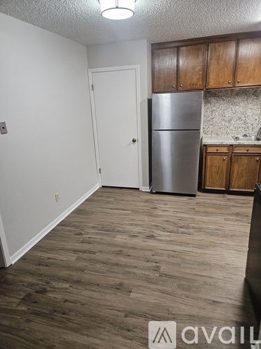 A kitchen with wooden cabinets and a stainless steel refrigerator.