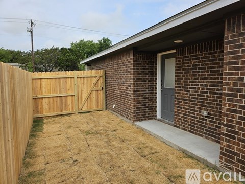 A backyard with a wooden fence and a brick house.