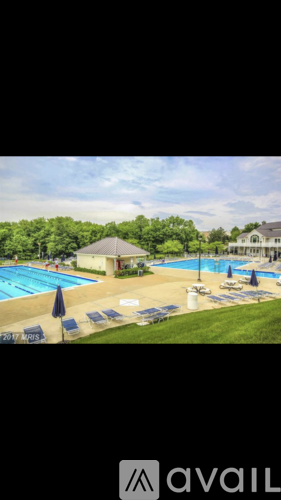 A pool with a sun umbrella and lounge chairs.