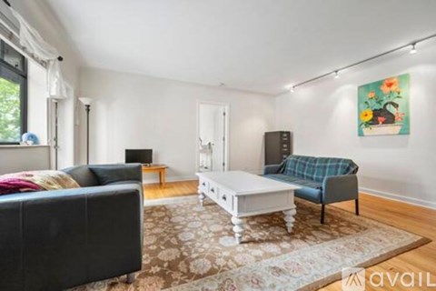 A living room with a black couch, a white coffee table, and a blue chair.