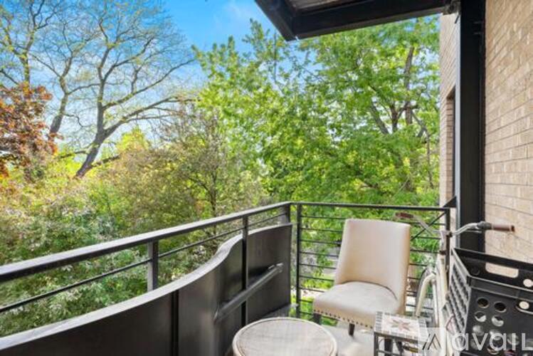 A balcony with a white chair and a table with a glass top.