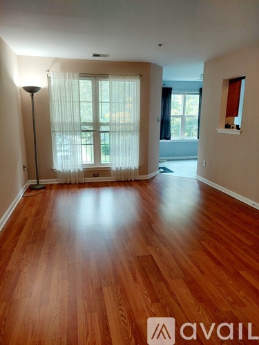 A room with wooden flooring and a window with curtains.