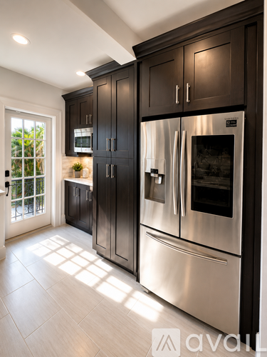 A modern kitchen with a stainless steel refrigerator and dark brown cabinets.
