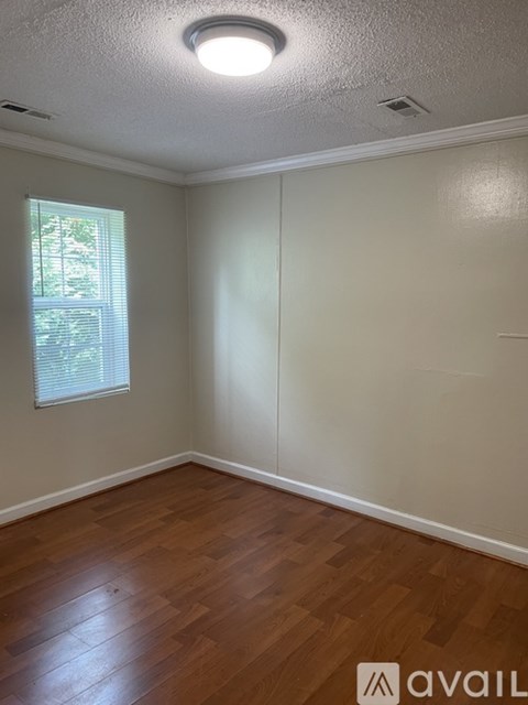 A room with wooden floors and a window with blinds.