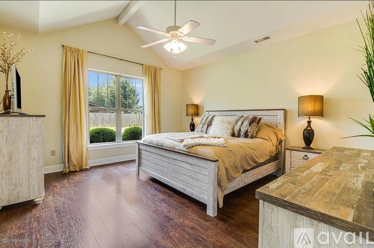 A bedroom with a bed, dresser, and window with curtains.