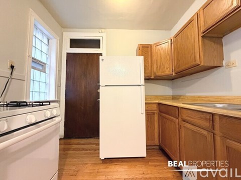 A white refrigerator in a kitchen with wooden cabinets.
