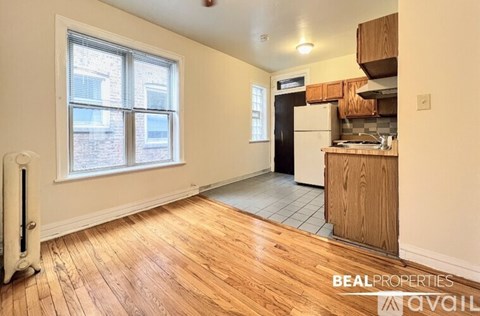 A room with wooden floors and a window overlooking a brick building.
