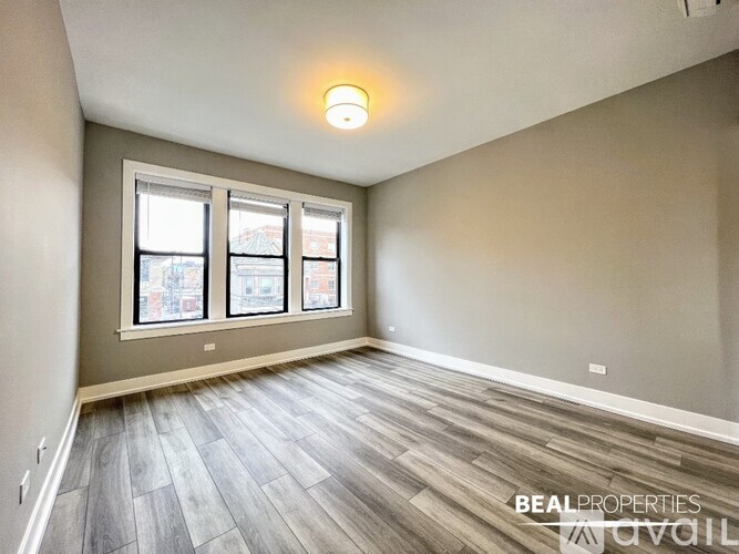 A spacious room with a large window and wooden flooring.
