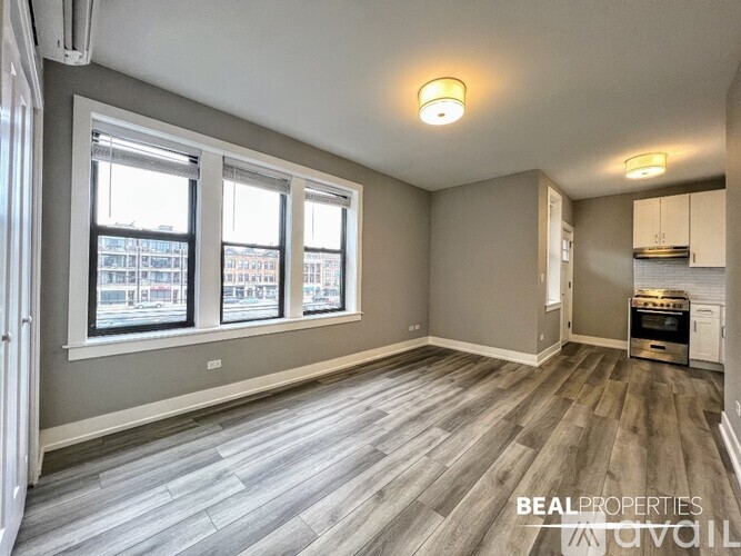 A spacious room with a wood floor and a window overlooking a cityscape.