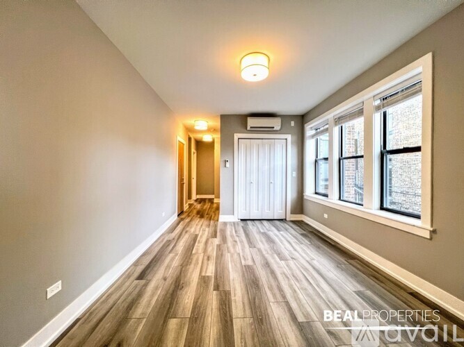 A spacious room with wooden flooring and a window on the right side.