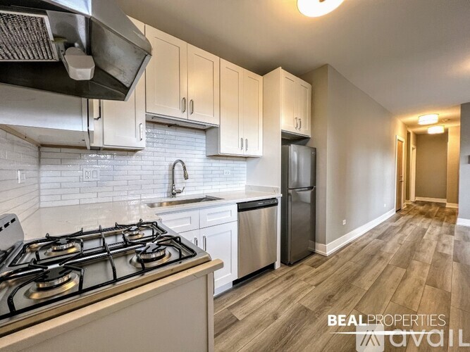 A kitchen with a stove, sink, and cabinets.