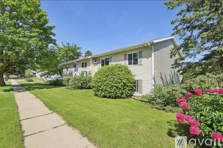 A house with a well-maintained lawn and a sidewalk in front.