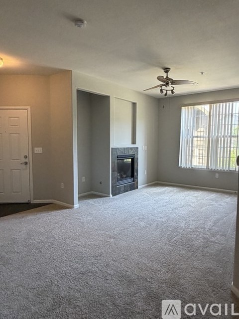 A living room with a fireplace and a ceiling fan.