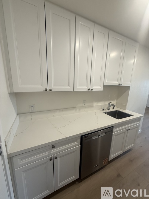 A kitchen with white cabinets and a sink.