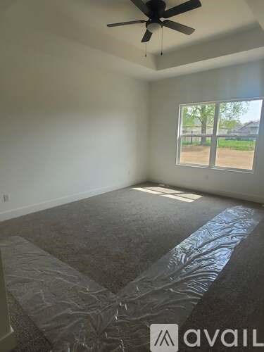 A room with a ceiling fan and a window covered with a tarp.