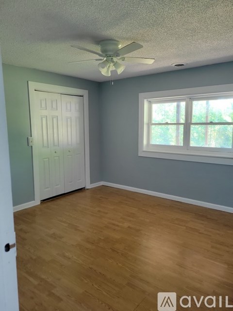 A room with a white door and a window with a ceiling fan.