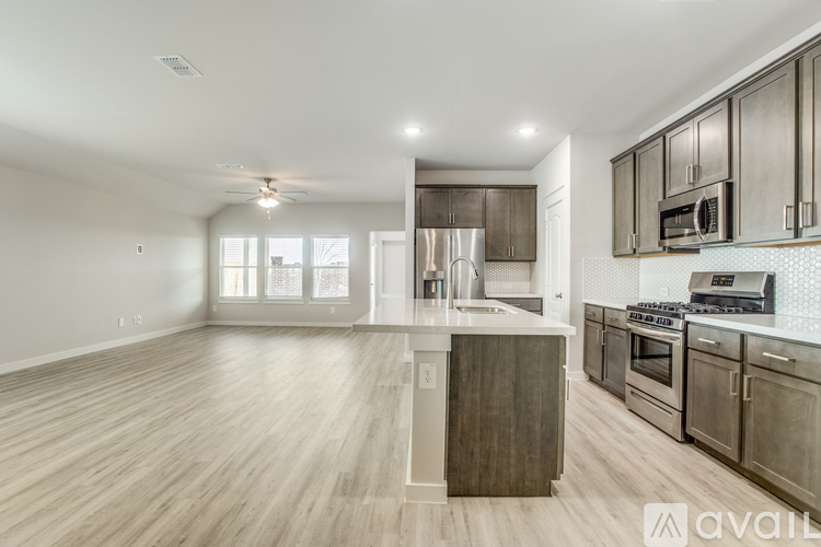 A spacious kitchen with stainless steel appliances and wooden flooring.