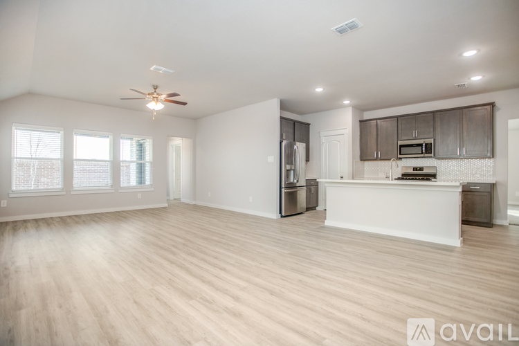 A spacious living room with a kitchen area in the background.